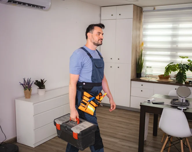 handyman walking in apartment carrying toolbox and wearing tool belt photo